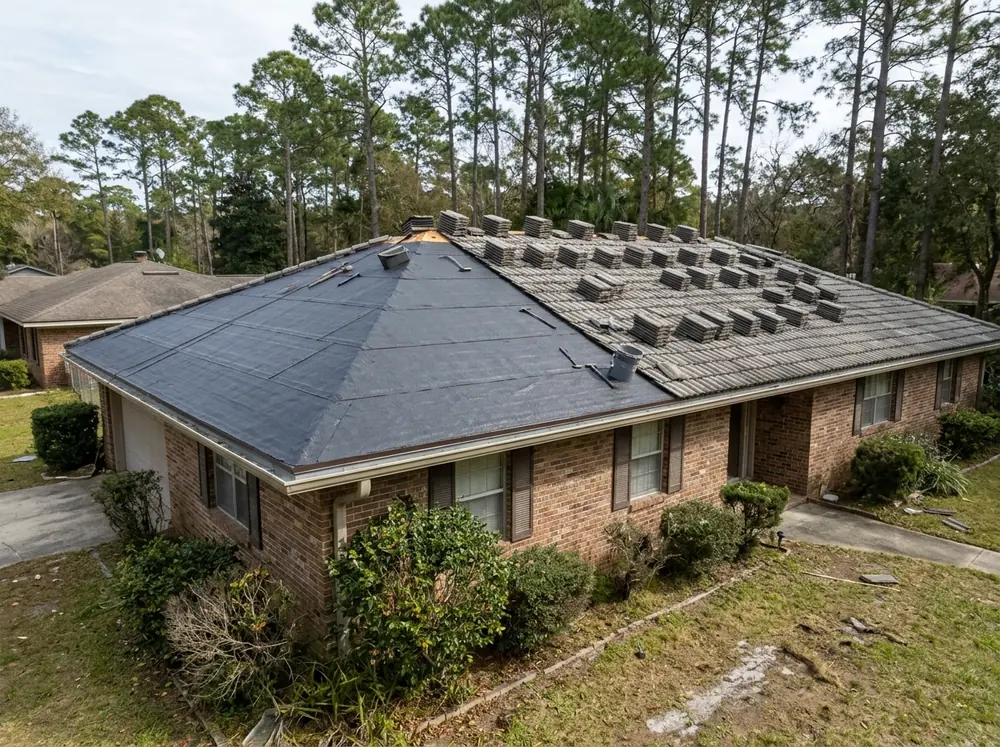 Section of concrete tile roof with tiles stacked on the roof and new self-adhered underlayment exposed on the deck
